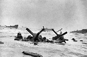 6 juni 1944. U.S. soldaten zoeken dekking achter een hindernis op Omaha Beach in Normandië. 